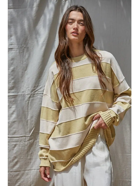 Woman wearing a yellow and white striped sweater against a plain background