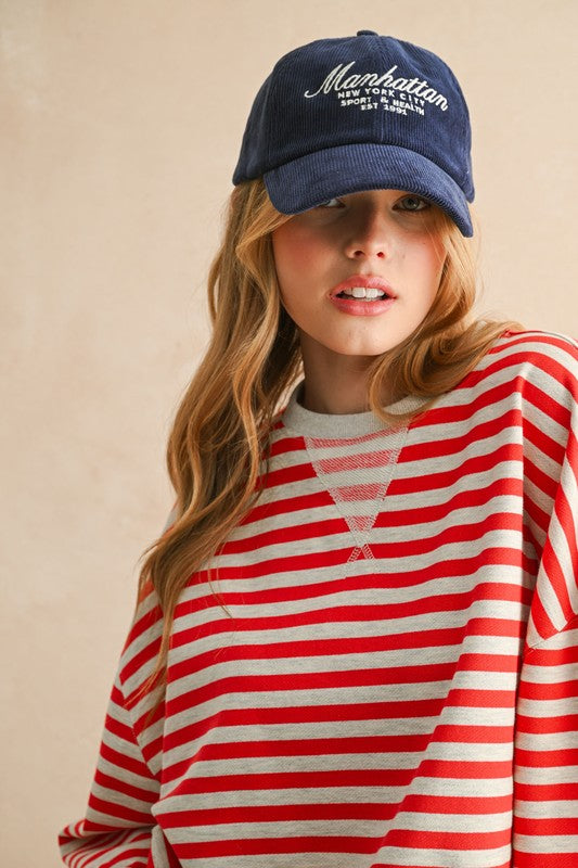 Woman wearing a red and white striped shirt with a blue cap on a beige background